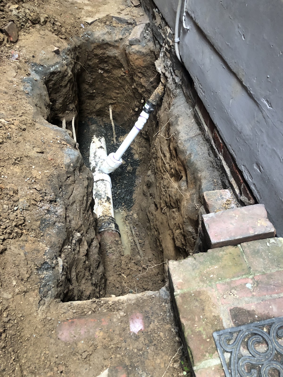 Sewer line replacement showing new PVC alongside old cast iron pipe
